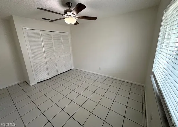 an empty room with windows and fan