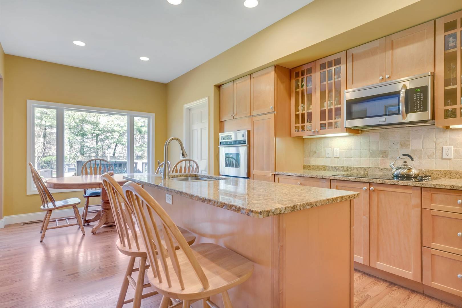 49 Bridle Path Westhampton Beach, NY 11978 - Photo 8 of 37 a kitchen with stainless steel appliances granite countertop a stove top oven a sink a dining table and chairs