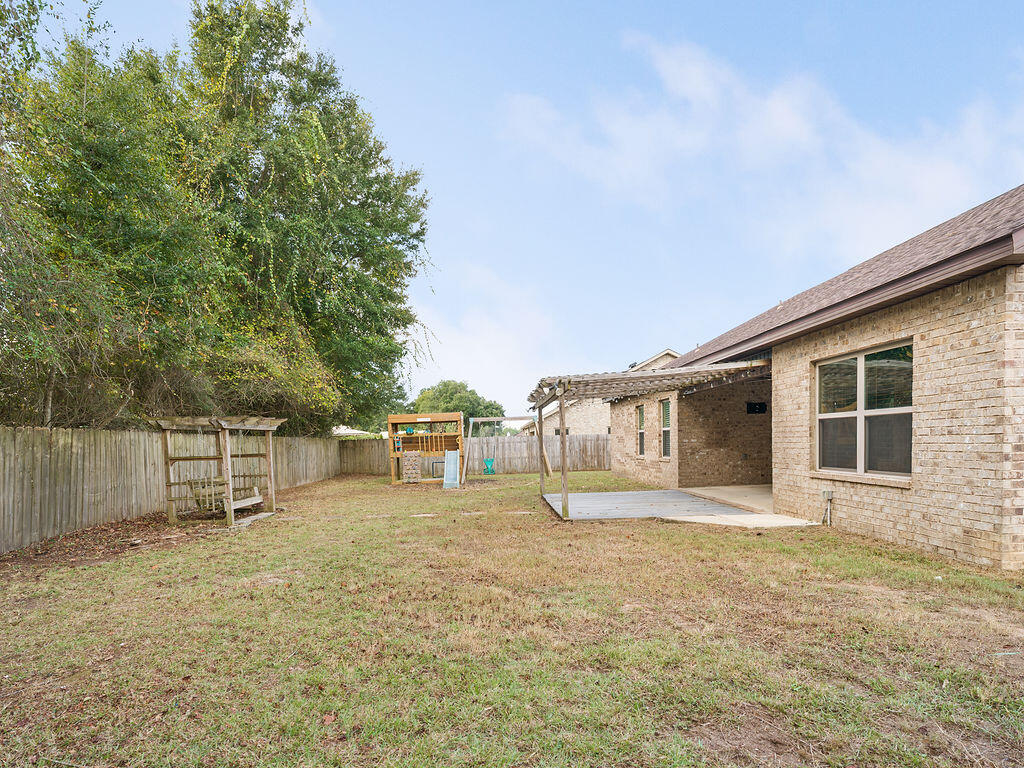 4889 Spears Street Pace, FL 32571 - Photo 24 of 25 a backyard of a house with barbeque oven and table and chairs