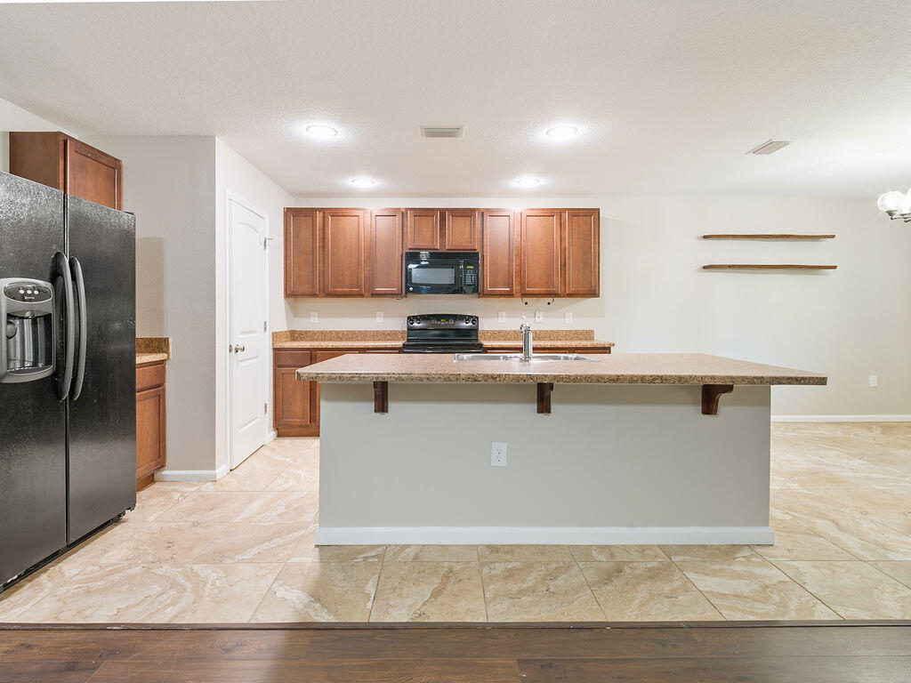 4889 Spears Street Pace, FL 32571 - Photo 9 of 25 a view of kitchen with stainless steel appliances granite countertop a stove top oven a sink and a refrigerator