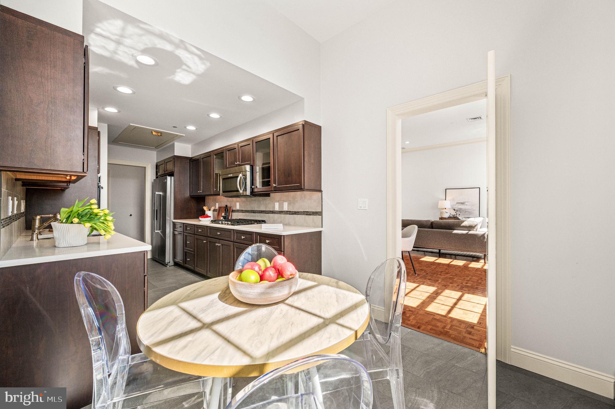 211 South 4th Street, Unit 301 Philadelphia, PA 19106 - Photo 12 of 42 a kitchen with stainless steel appliances kitchen island granite countertop a refrigerator a stove a microwave oven with a dining table and chairs with wooden floor