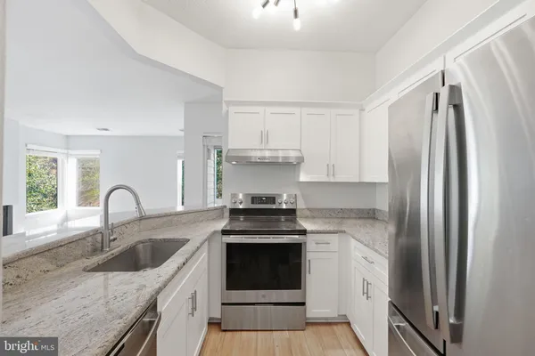 a kitchen with granite countertop a stove sink and refrigerator