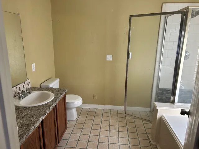 a bathroom with a granite countertop sink a mirror and a shower