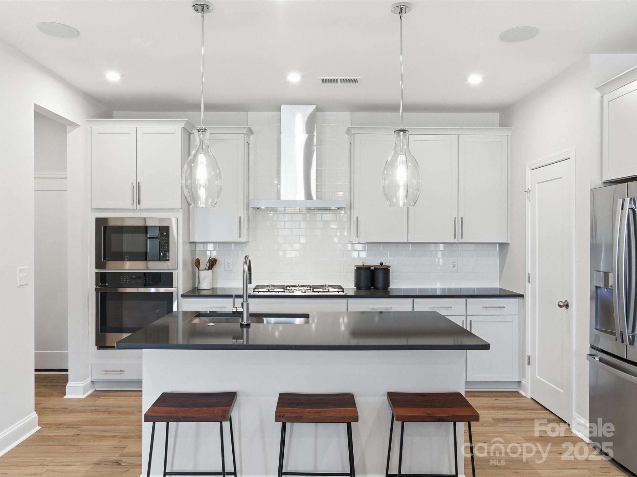 492 Nash Street Fort Mill, SC 29715 - Photo 11 of 28 a kitchen with stainless steel appliances granite countertop a sink a stove a refrigerator and island with wooden floor
