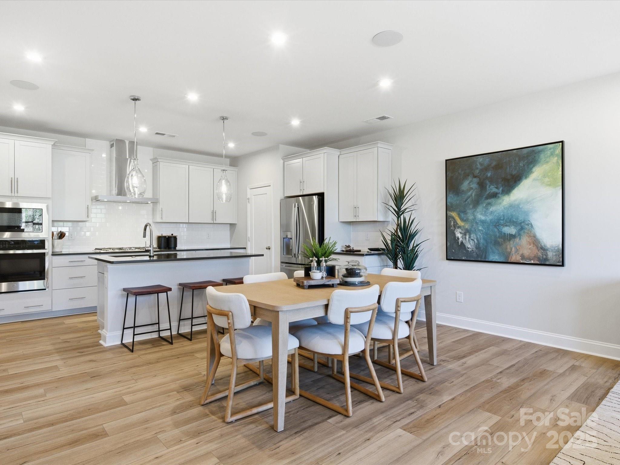 492 Nash Street Fort Mill, SC 29715 - Photo 7 of 28 a kitchen with stainless steel appliances kitchen island granite countertop a wooden table chairs and wooden floor