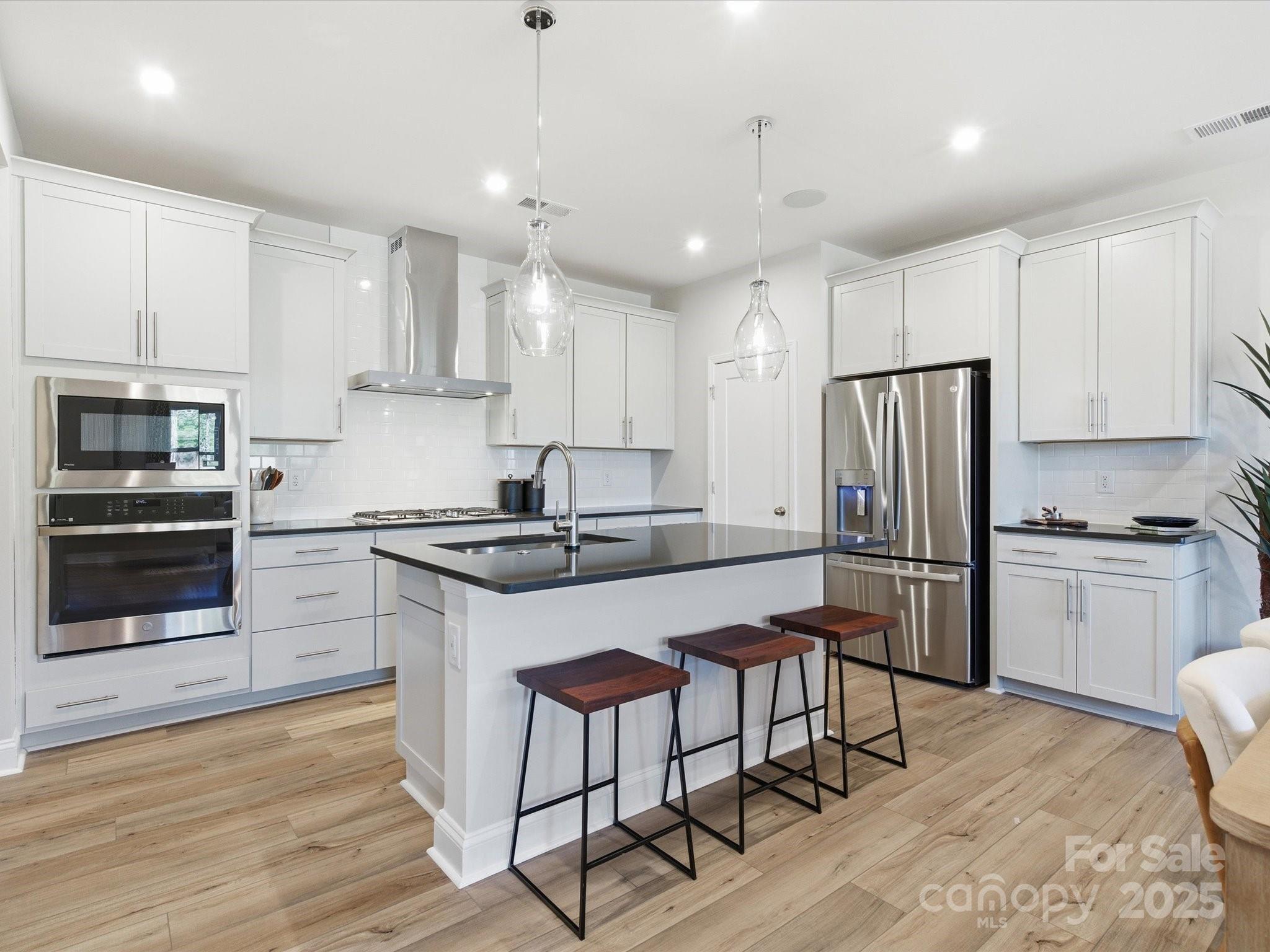 492 Nash Street Fort Mill, SC 29715 - Photo 10 of 28 a kitchen with stainless steel appliances granite countertop a stove a refrigerator a oven a sink a stove and white cabinets with wooden floor