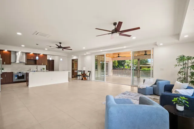 a living room with furniture and a large window with kitchen view