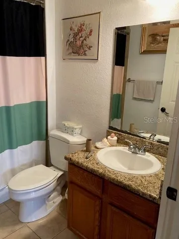 a bathroom with a granite countertop toilet sink and mirror