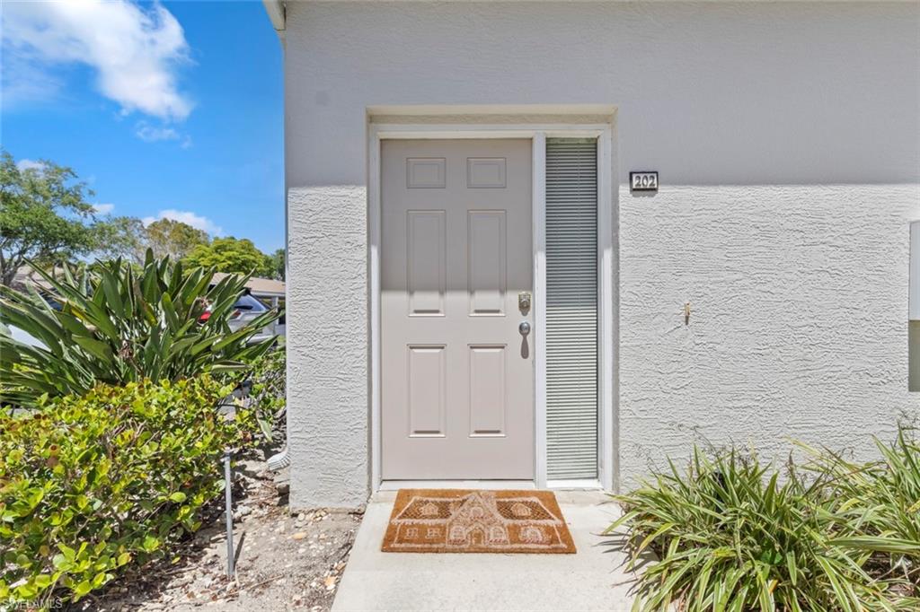 6812 Satinleaf Road South, Unit 202 Naples, FL 34109 - Photo 3 of 49 View of exterior entry featuring stucco siding