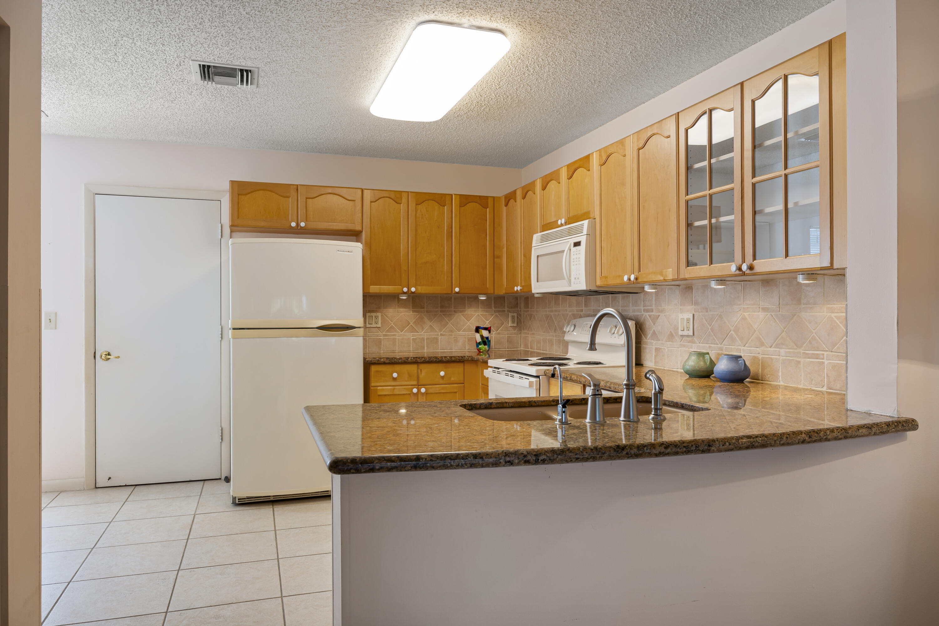 105 Ocean Dunes Circle Jupiter, FL 33477 - Photo 11 of 40 a kitchen with sink a refrigerator and cabinets