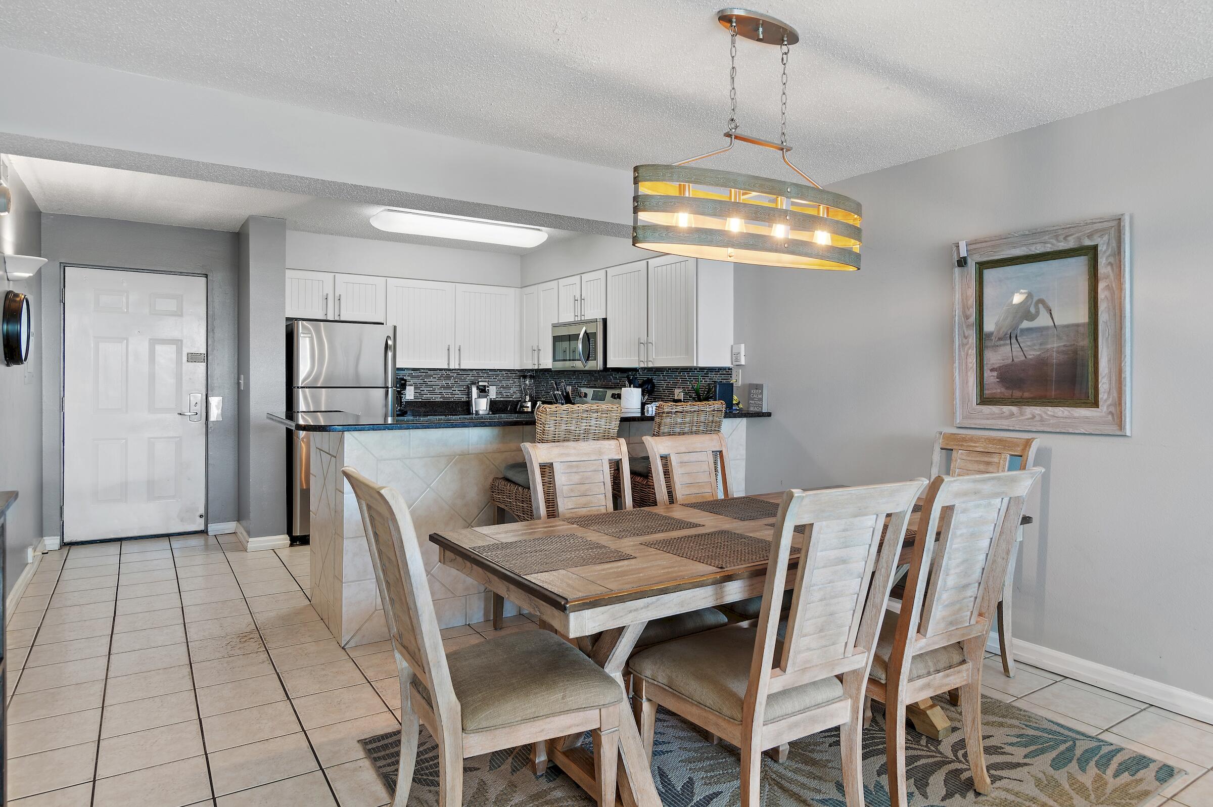 1002 Highway 98, Unit 217 Destin, FL 32541 - Photo 16 of 48 a dining room with stainless steel appliances kitchen island granite countertop a dining table chairs and a refrigerator