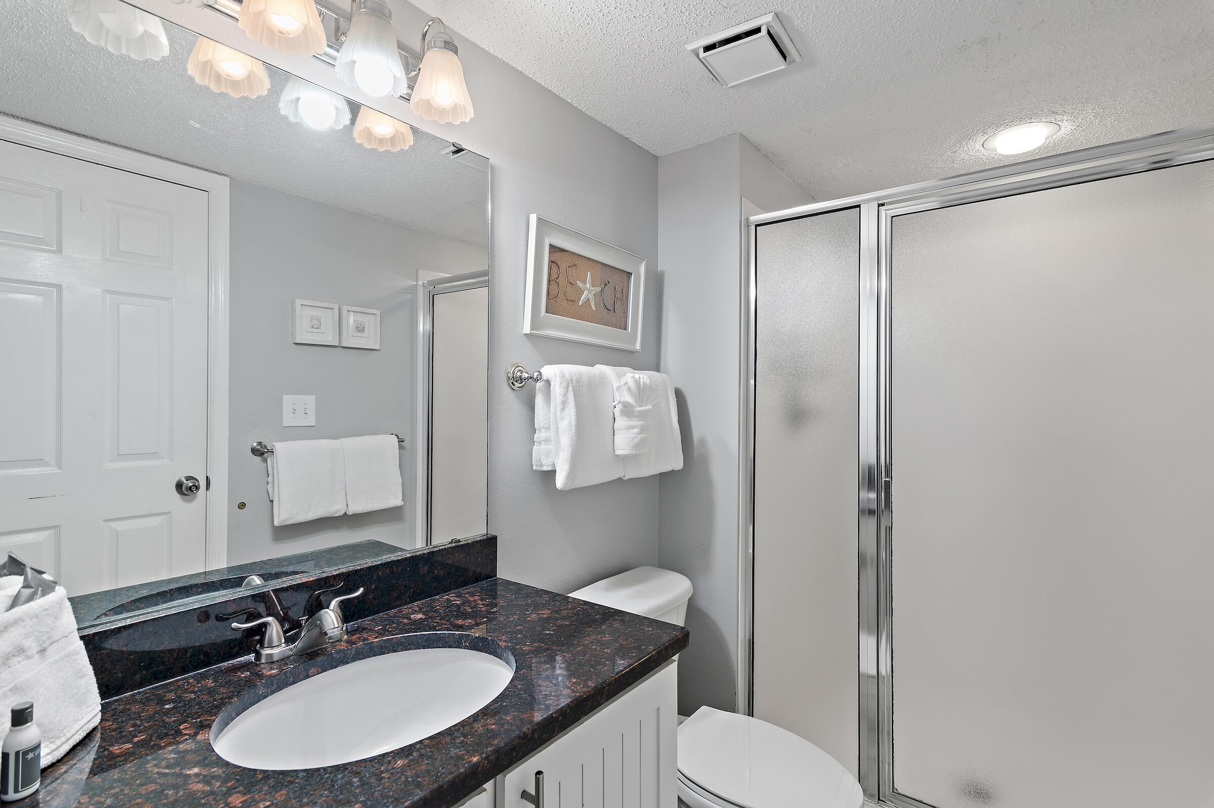 1002 Highway 98, Unit 217 Destin, FL 32541 - Photo 36 of 48 a bathroom with a granite countertop sink toilet a mirror and shower