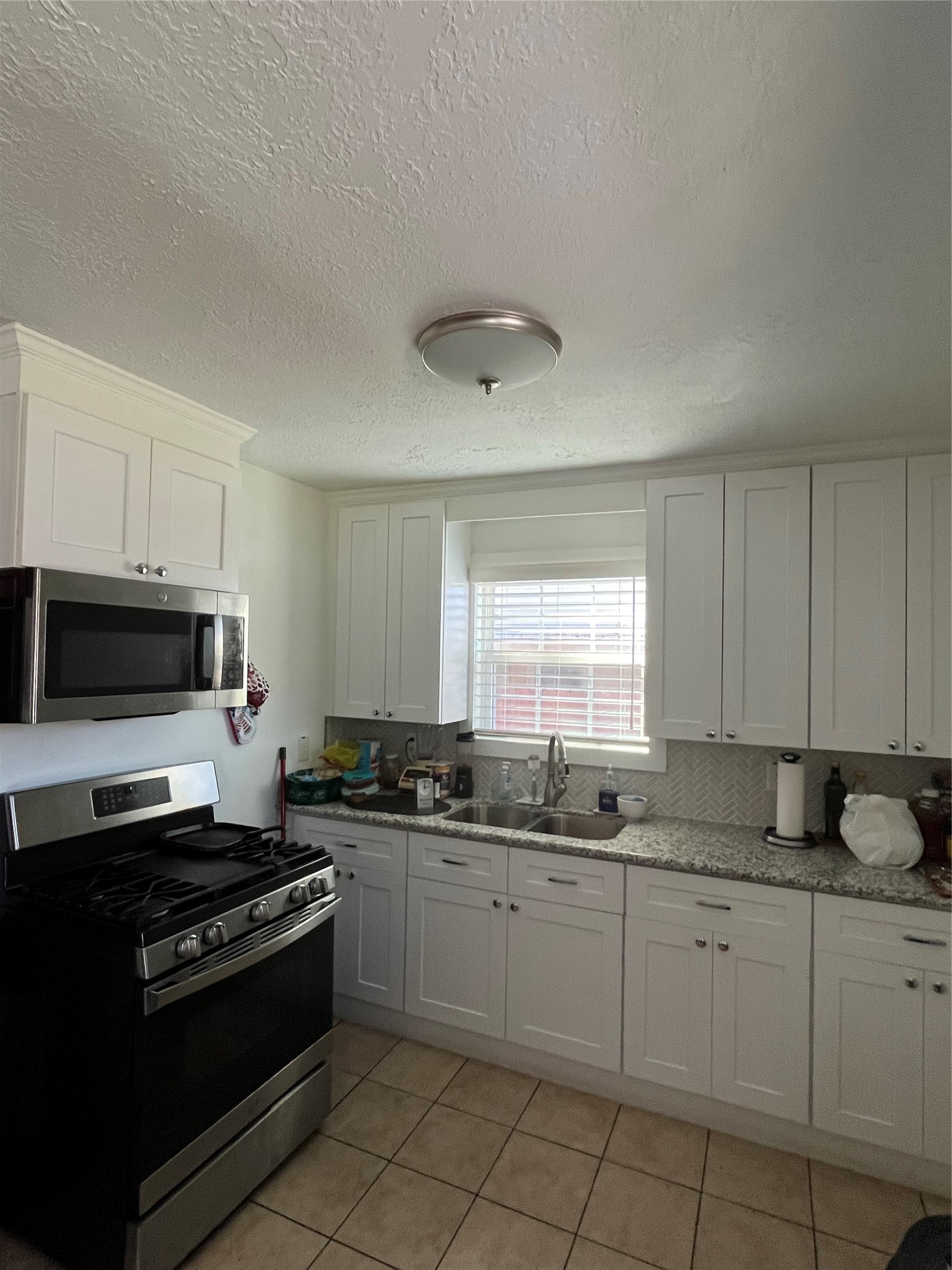 208 Oddo Street Houston, TX 77022 - Photo 3 of 10 a kitchen with stainless steel appliances granite countertop a stove a sink and a microwave