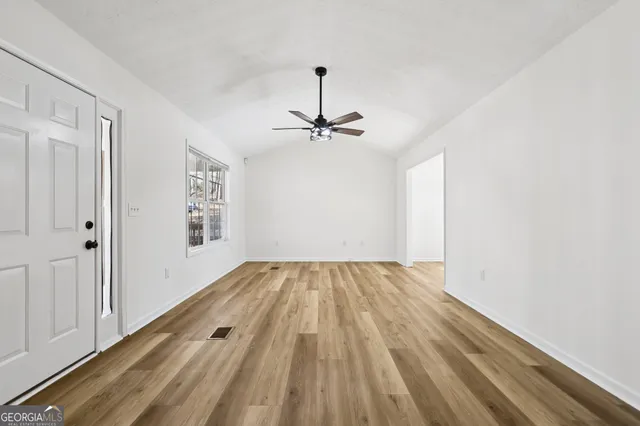 a view of a room with wooden floor a ceiling fan