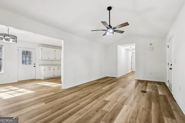 a view of empty room with wooden floor and ceiling fan