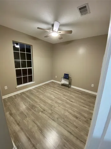 a view of a room with a hardwood and ceiling fan