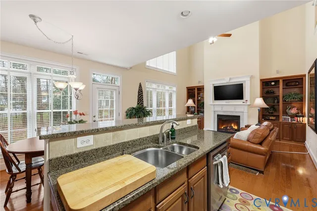 a kitchen with granite countertop a stove and a sink with couches wooden floor