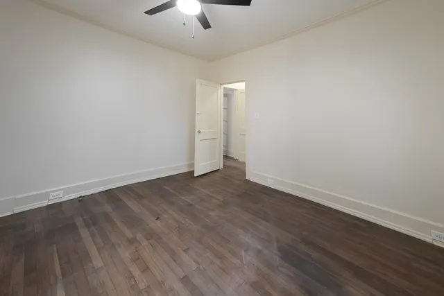 an empty room with wooden floor chandelier fan and windows