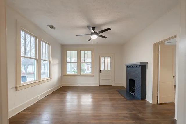 a view of empty room with wooden floor and a window