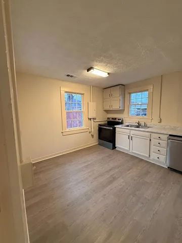 an empty room with wooden floor and windows