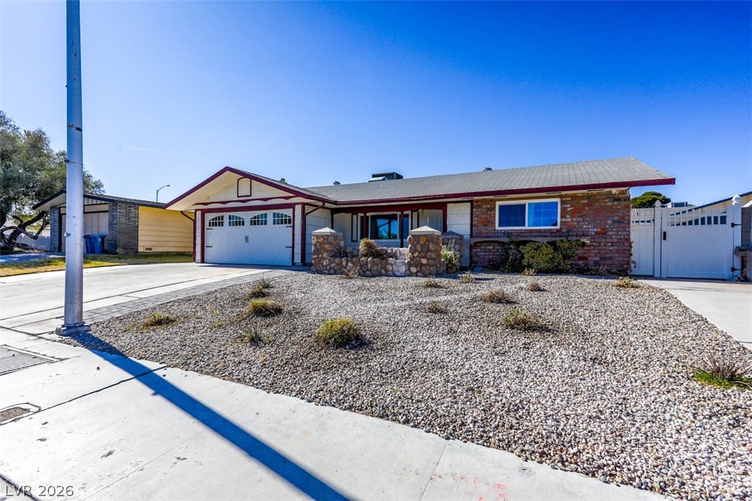 228 Redstone Street Las Vegas, NV 89145 - Photo 3 of 31 Ranch-style house featuring driveway, brick siding, an attached garage, and a gate
