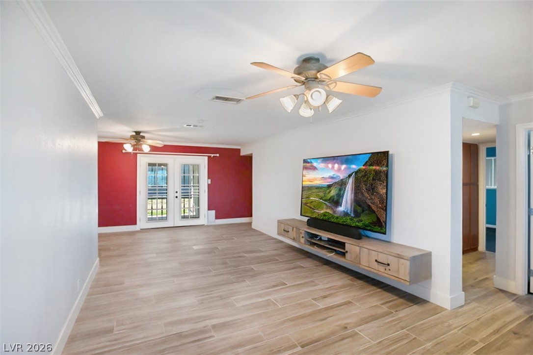 228 Redstone Street Las Vegas, NV 89145 - Photo 6 of 31 Unfurnished living room with wood tiled floors, a ceiling fan, french doors, and crown molding