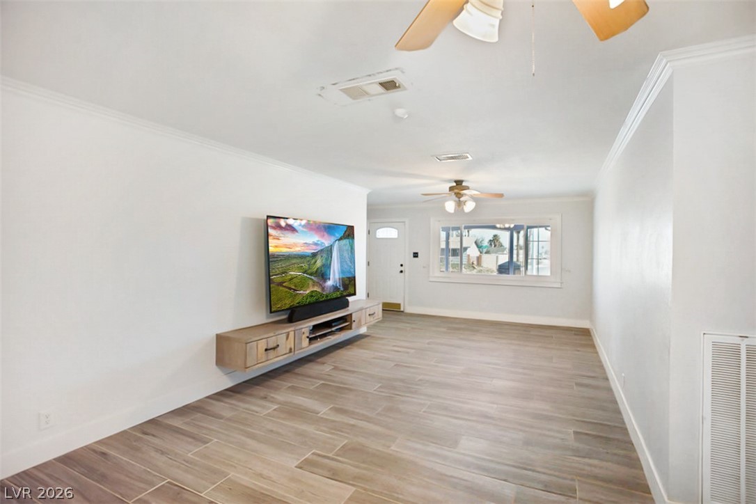 228 Redstone Street Las Vegas, NV 89145 - Photo 7 of 31 Unfurnished living room with wood tiled floors, crown molding, and a ceiling fan