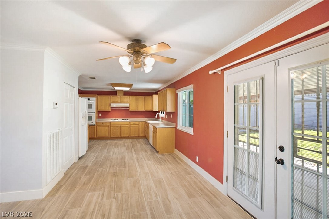 228 Redstone Street Las Vegas, NV 89145 - Photo 8 of 31 Kitchen with light wood-style flooring, light countertops, crown molding, ceiling fan, and white appliances