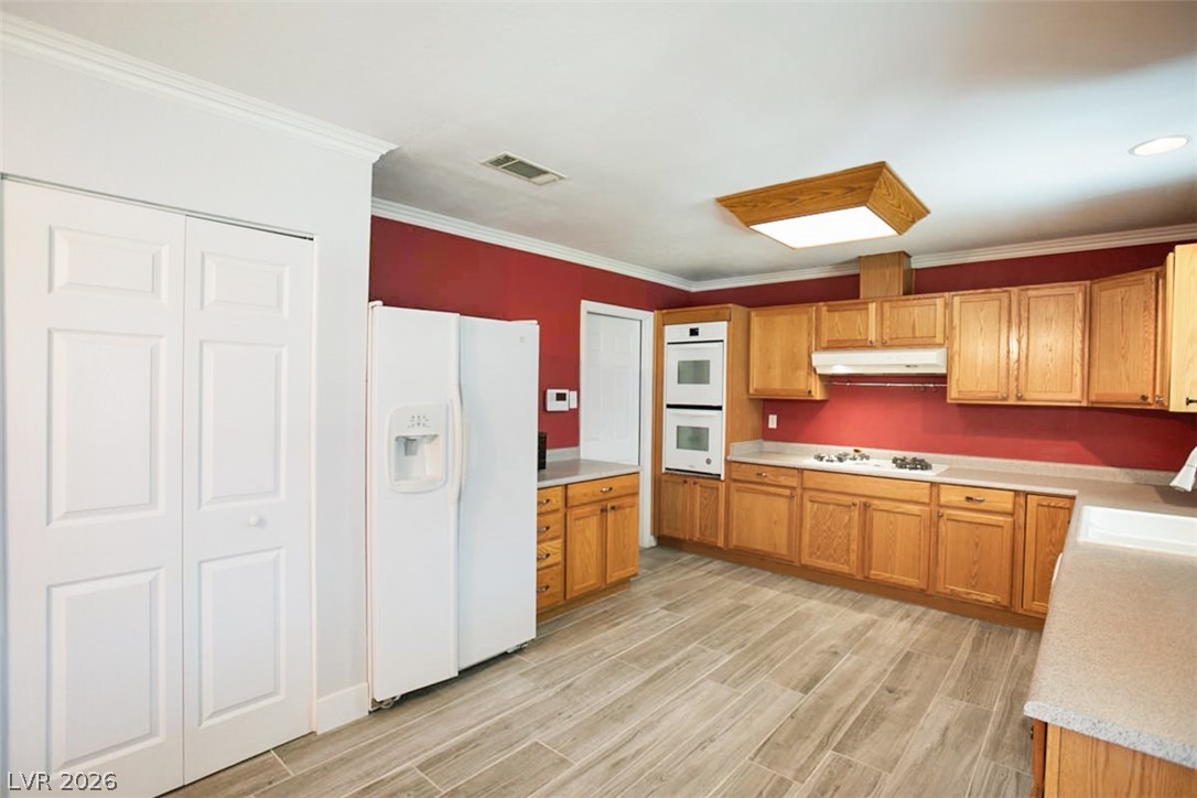 228 Redstone Street Las Vegas, NV 89145 - Photo 9 of 31 Kitchen with white appliances, light countertops, wood tiled floors, crown molding, and wood finish cabinets