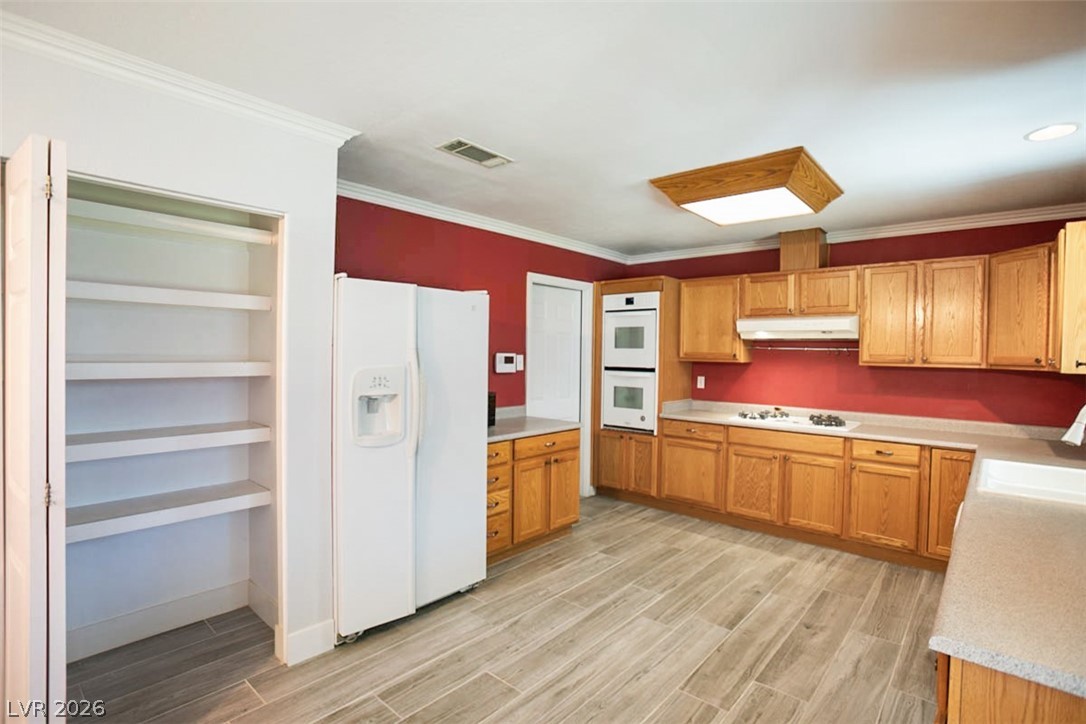 228 Redstone Street Las Vegas, NV 89145 - Photo 10 of 31 Kitchen with white appliances, light countertops, crown molding, wood tiled floors, and built in features
