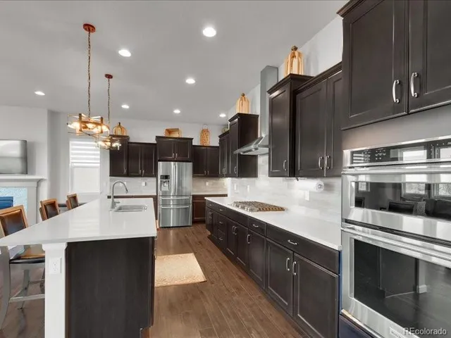a kitchen with stainless steel appliances granite countertop a sink a stove and a refrigerator