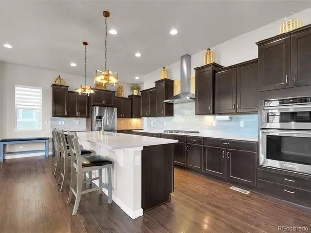 a kitchen with stainless steel appliances kitchen island granite countertop a table chairs and a sink