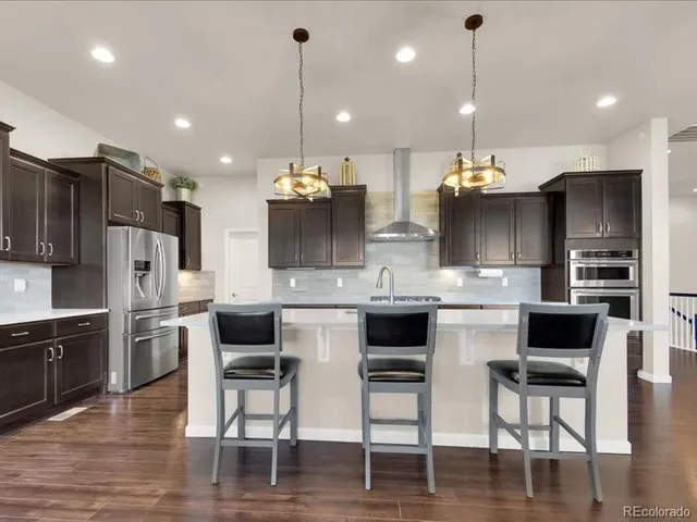 a kitchen with granite countertop a refrigerator and a stove top oven
