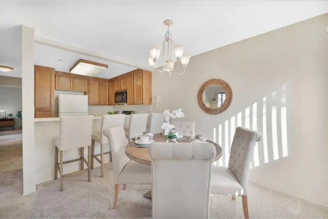 a dining room with wooden floor a chandelier a wooden table and chairs