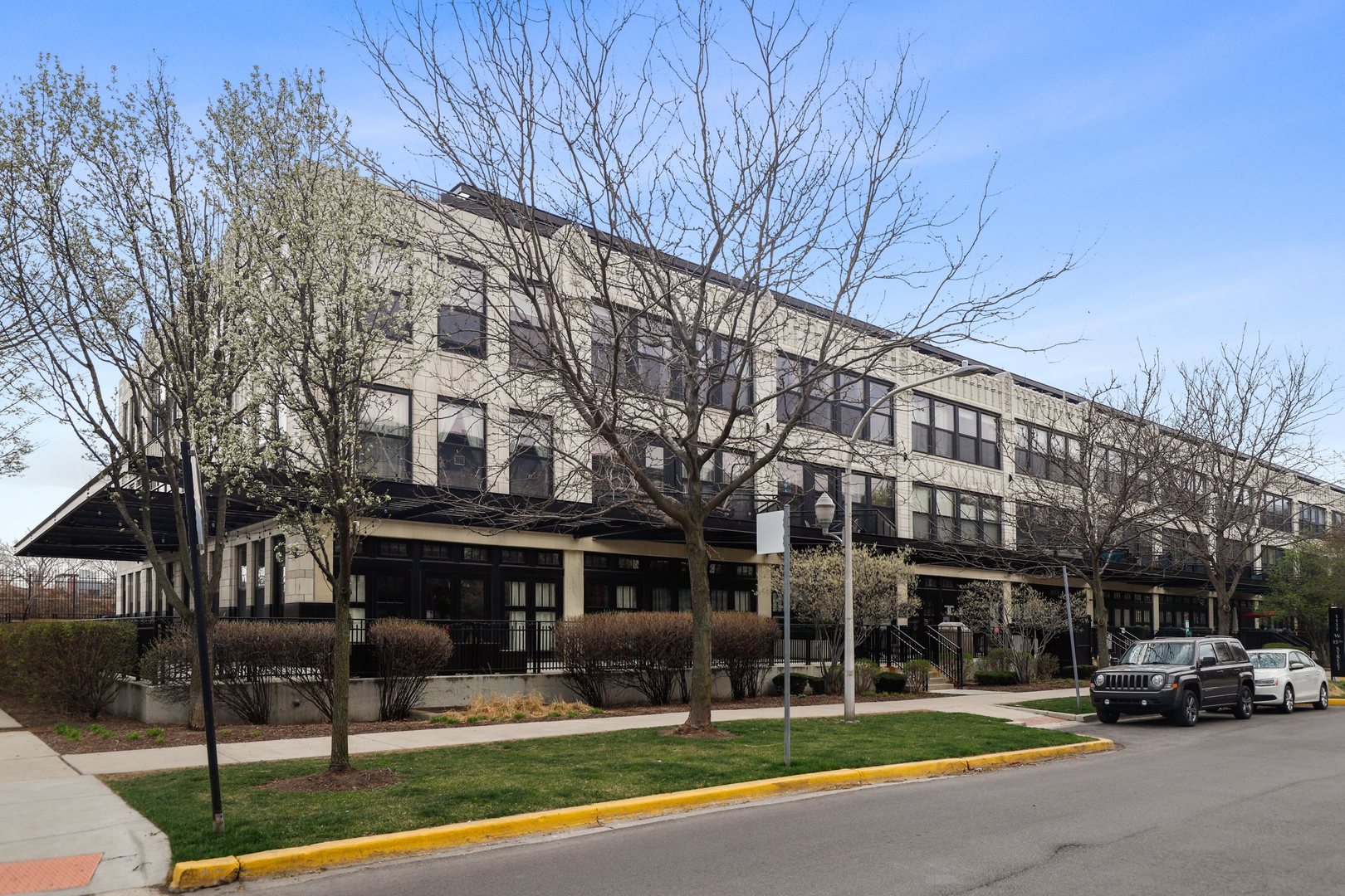 1111 West 15th Street, Unit 113 Chicago, IL 60608 - Photo 3 of 34 a view of a building with a yard and car parked