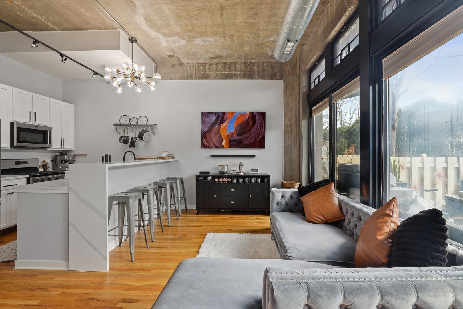 1111 West 15th Street, Unit 113 Chicago, IL 60608 - Photo 4 of 34 a living room with furniture a chandelier and a flat screen tv