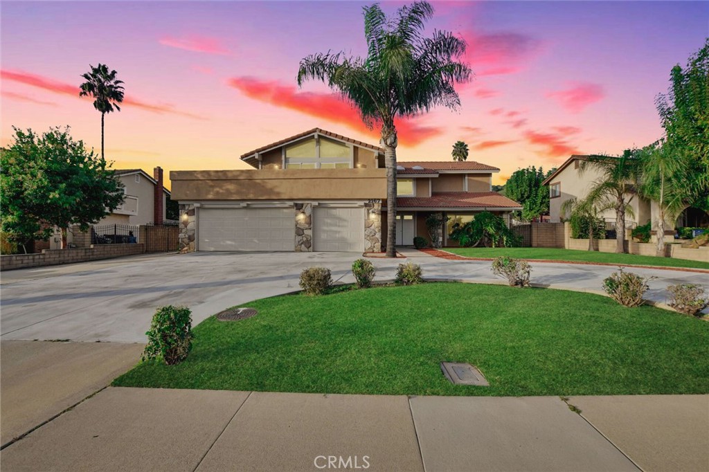 a front view of a house with a garden and palm tree