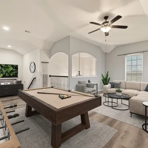 a view of an empty room with wooden floor and a ceiling fan