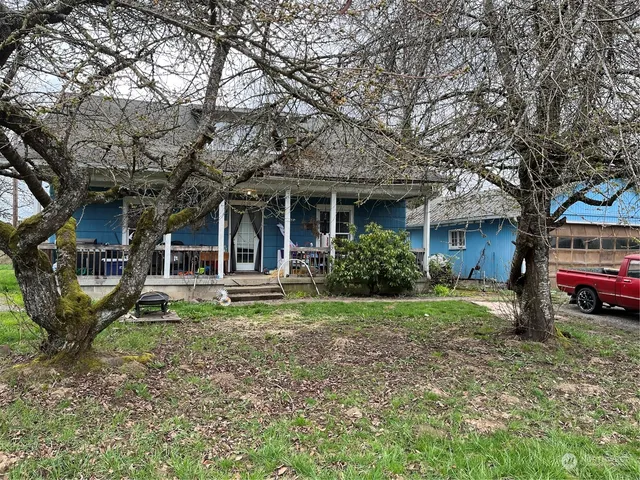 a view of a house with a yard and large trees