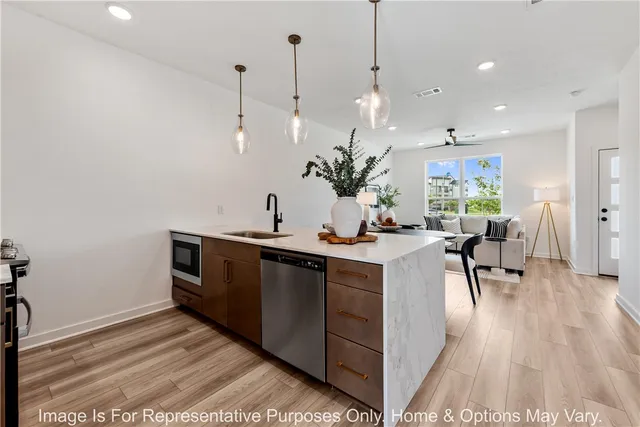 a kitchen with stainless steel appliances granite countertop a sink a stove and a wooden floors