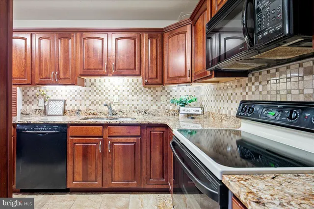 a kitchen with granite countertop stainless steel appliances wooden cabinets and a sink