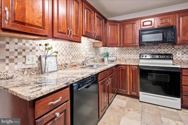 a kitchen with granite countertop a sink and a refrigerator