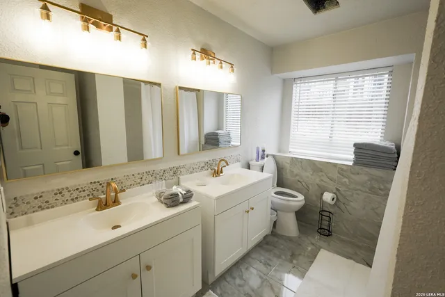 a bathroom with a double vanity sink mirror and toilet