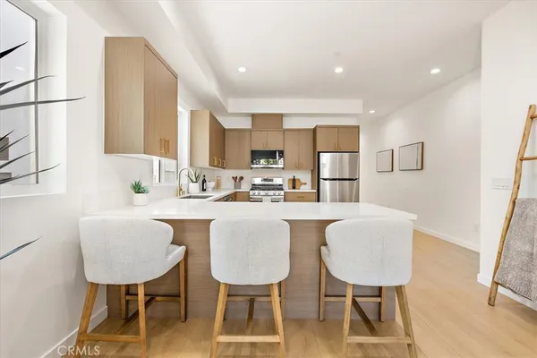 a large white open kitchen with stainless steel appliances kitchen island granite countertop a sink counter space cabinets and a large window