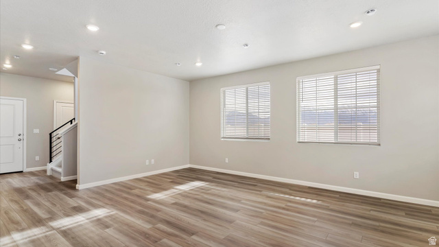82 Provo River Road, Unit 251 Saratoga Springs, UT 84045 - Photo 3 of 32 Spacious living area featuring wood-finish flooring, two large windows with blinds, recessed lighting, and a modern staircase with black metal railings