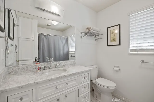 a bathroom with a granite countertop sink a toilet and a mirror
