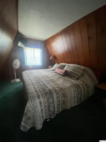 a bed sitting in a spacious bedroom next to a window and dresser