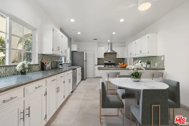 a kitchen with granite countertop white cabinets a counter and chairs