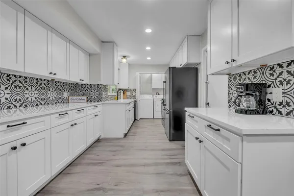 a kitchen with white cabinets and refrigerator