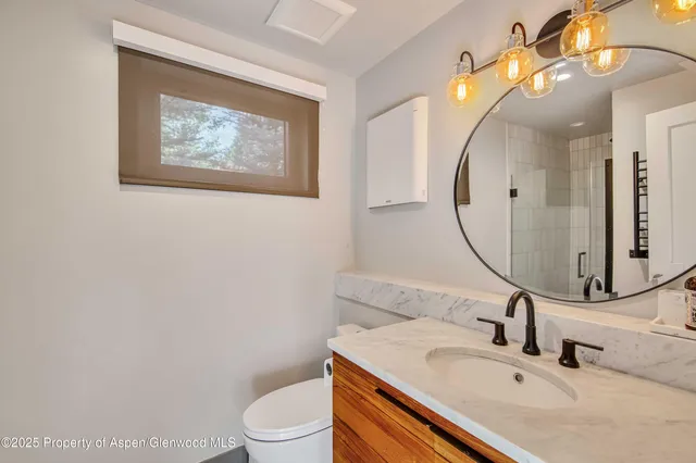 a bathroom with a toilet sink vanity and mirror